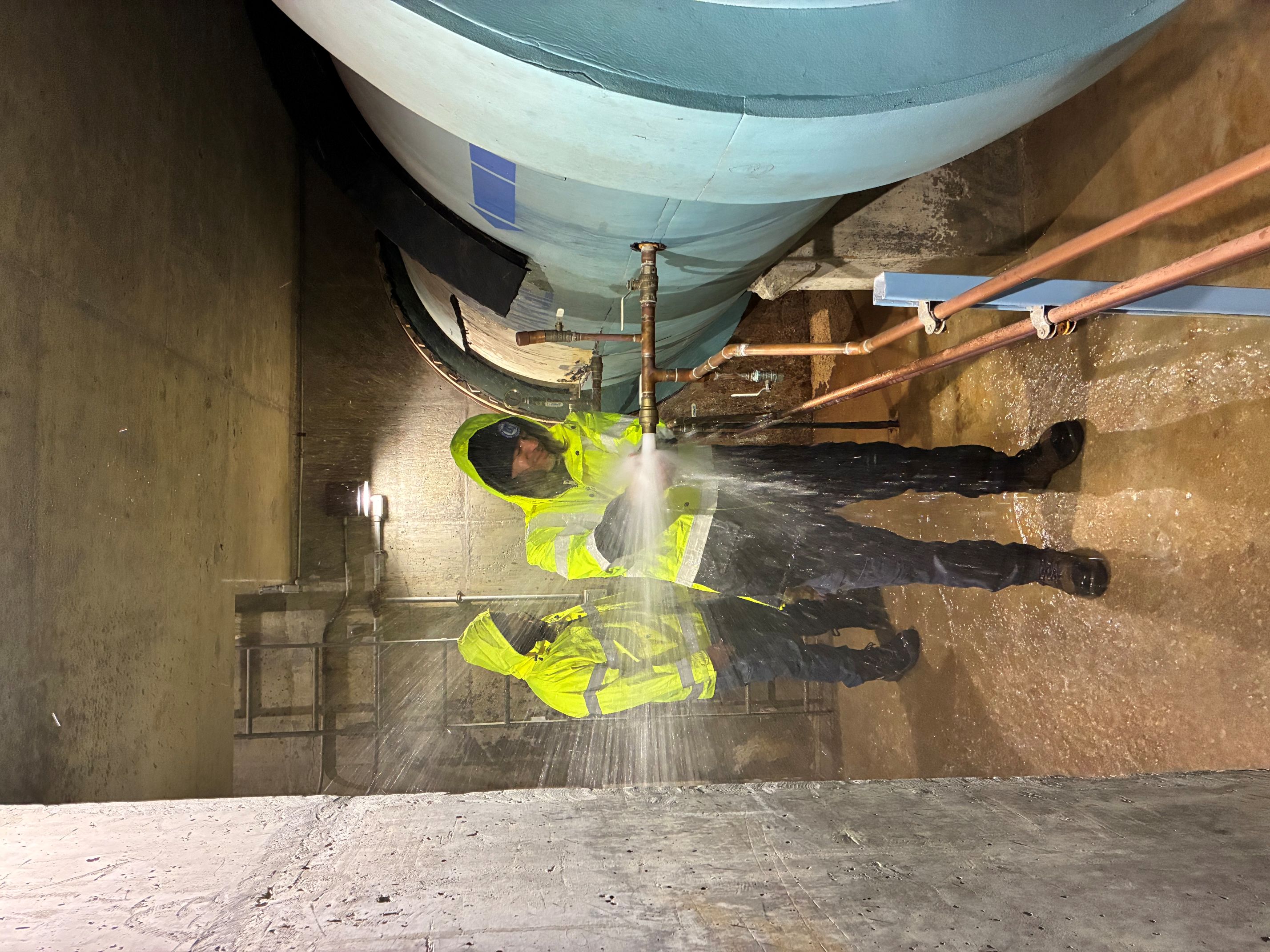 person being sprayed by water from large pipe